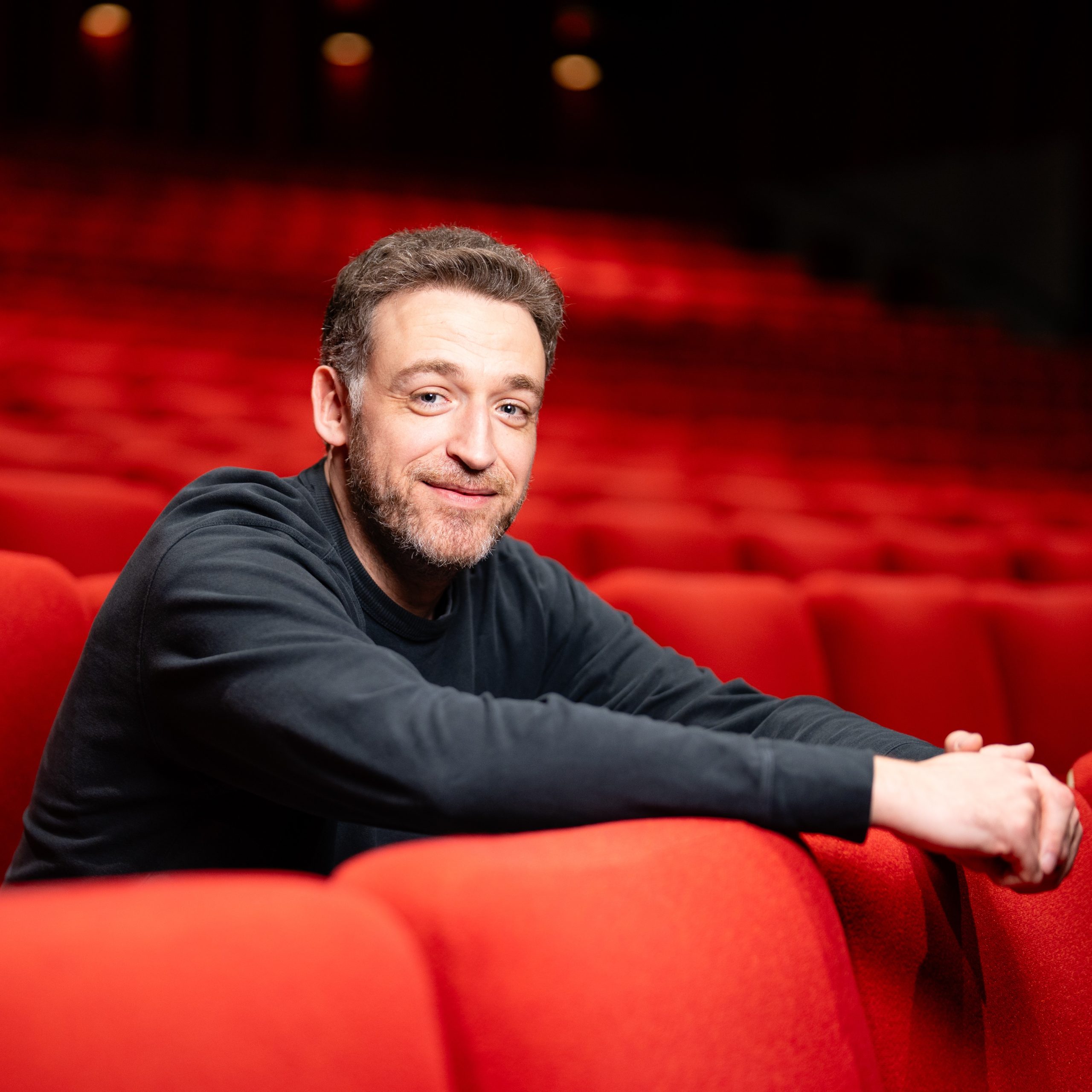 Dan Soder sitting with his hands draped over a row of red chairs